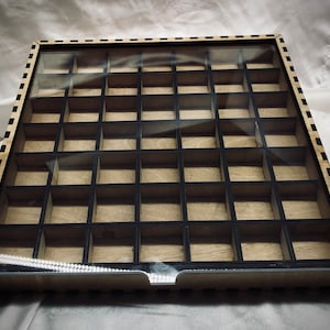 May include: A wooden box with a clear glass lid and a black grid pattern inside. The box has a black and white checkered border.