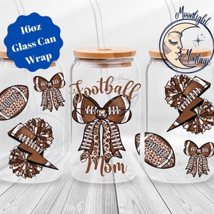 Op de afbeelding: Drie 473 ml glazen blikverpakkingen met een voetbalthema. De verpakkingen hebben een bruin en wit luipaardprintontwerp met voetballen, strikken en cheerleading pompoenen. Eén verpakking zegt "Football Mom".