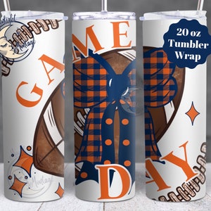 May include: A white 20 oz tumbler wrap featuring a football and the words "GAME DAY" in orange. The design includes a navy blue and orange plaid bow. The tumbler has a straw and a lid.