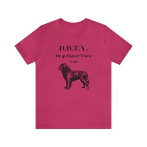 Puede incluir: Una camiseta rosa con el texto "D.B.T.Y. Dogs Bigger Than You" y una ilustración en blanco y negro de un perro.