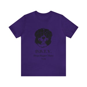 Puede incluir: Camiseta morada con una ilustración negra de un perro de montaña bernés y el texto "D.B.T.Y. Dogs Bigger Than You."