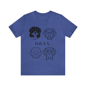 Puede incluir: Una camiseta azul real con cuatro ilustraciones en blanco y negro de razas de perros. El texto "D.B.T.Y." está impreso debajo de las ilustraciones.