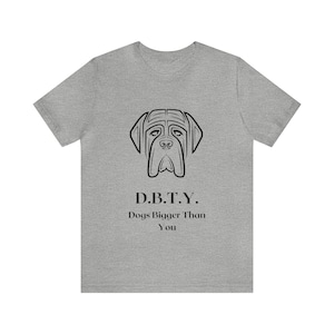 Puede incluir: Una camiseta gris con una ilustración negra de la cabeza de un perro y el texto "D.B.T.Y. Dogs Bigger Than You".
