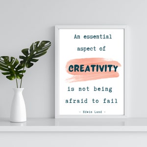 May include: White framed art print with the quote "An essential aspect of creativity is not being afraid to fail." The word "CREATIVITY" is in navy blue over a peach-colored brushstroke. A white vase with green leaves is to the left.