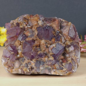 May include: A large amethyst crystal cluster with a purple and brown color. The crystal is rough and has a natural, raw look.