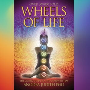 May include: Book cover with a purple, yellow, and orange background. The title is "Wheels of Life" in large, gold letters. The subtitle is "The Classic Guide to the Chakra System" in smaller gold letters. The author's name is "Anodea Judith PhD" in gold letters. The cover features a woman in a yoga pose with a rainbow of colors representing the chakras.