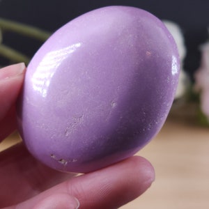 May include: A smooth, polished purple amethyst stone, shaped like an oval, with a light sheen.