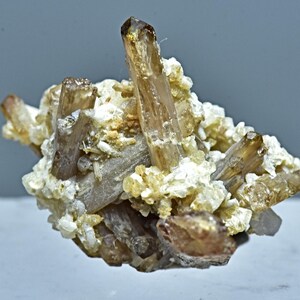 May include: A cluster of brown and clear crystals on a white matrix. The crystals are sharp and well-formed.