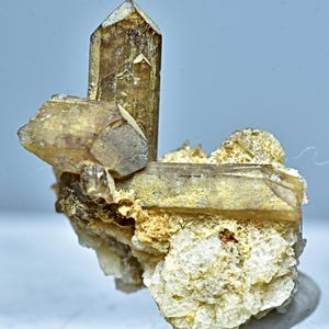 May include: A cluster of brown, translucent quartz crystals on a white, rocky matrix. The crystals are sharp and well-formed, with a glassy luster.