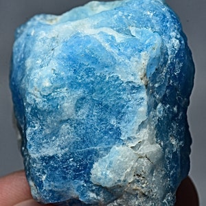 May include: A rough, blue and white mineral specimen. The mineral has a cloudy, opaque appearance with a blue hue.