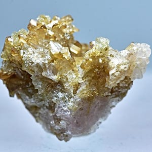 May include: A cluster of light brown and clear quartz crystals with a pink hue at the base.
