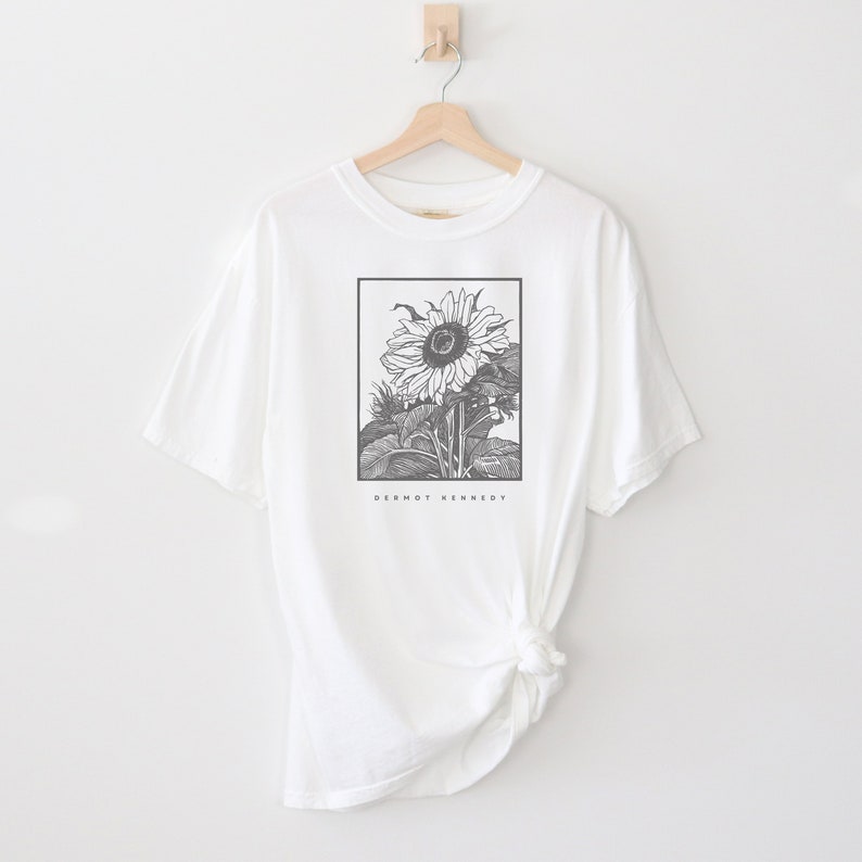 May include: White t-shirt with a black and white illustration of a sunflower. The text "Dermot Kennedy" is printed below the sunflower.
