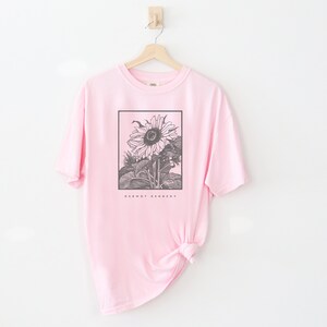 May include: Pink t-shirt with a black and white illustration of a sunflower and the text "Dermot Kennedy".