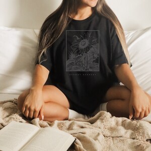 May include: A black oversized t-shirt with a white graphic of a sunflower and the text "Dermot Kennedy".