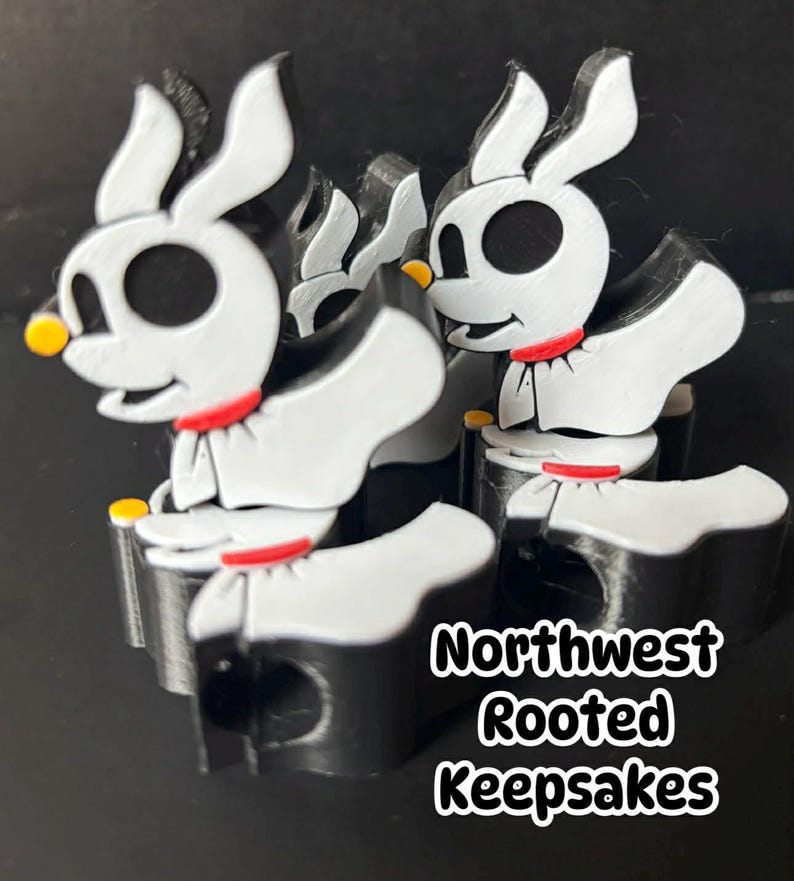 Op de afbeelding: Een groep witte, zwarte en rode Zero-beeldjes uit The Nightmare Before Christmas. Elk beeldje heeft een zwart lichaam, witte ledematen en een witte kop met zwarte ogen. De beeldjes hebben een rode kraag en gele neus. De tekst "Northwest Rooted Keepsakes" is zichtbaar.