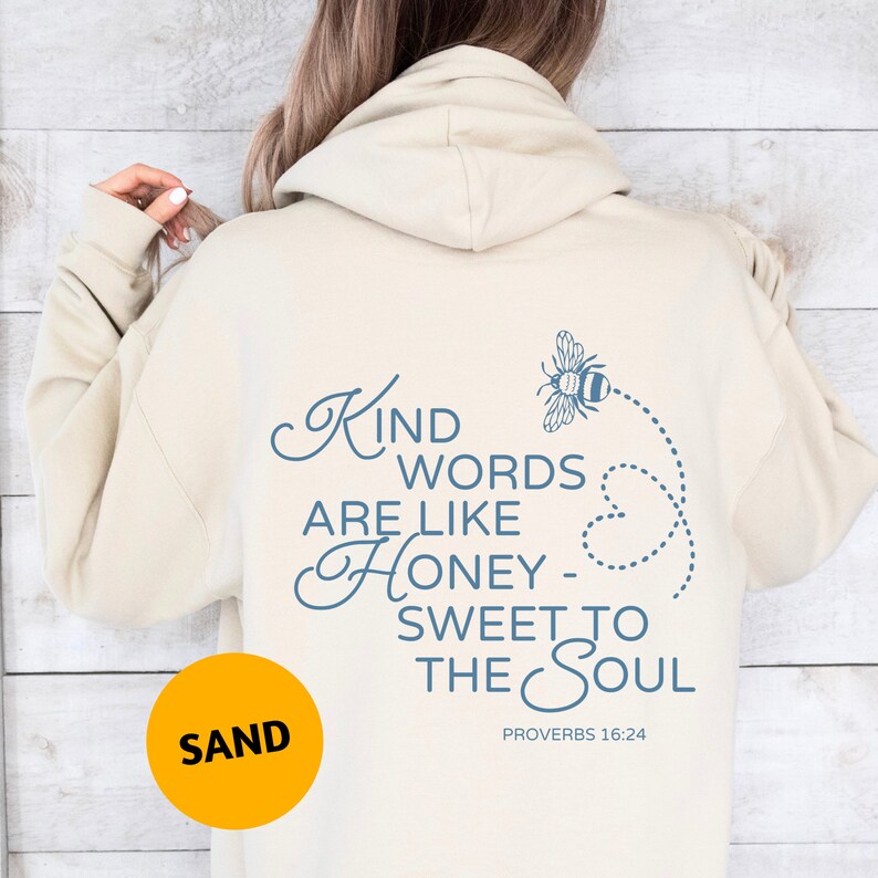 May include: A beige hoodie with a blue graphic on the back that says "Kind words are like honey - sweet to the soul" with a bee illustration and the text "Proverbs 16:24".