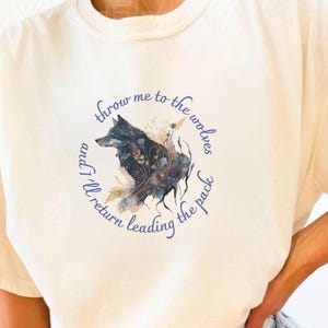 May include: A white t-shirt with a wolf graphic and the text "Throw me to the wolves and I'll return leading the pack".