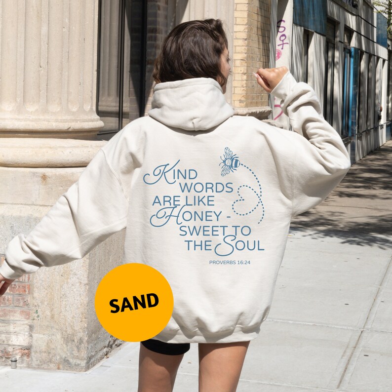 May include: A white hoodie with a blue graphic that says "Kind words are like honey - sweet to the soul" and "Proverbs 18:24". A bee with wings is flying above the text.