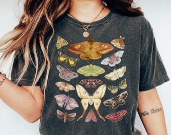 May include: A dark grey t-shirt with a vintage-style print of various butterflies and moths in shades of brown, yellow, green, blue, and purple.