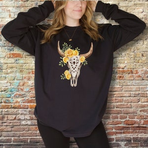 May include: Black long-sleeved sweatshirt with a white floral skull design featuring yellow roses.