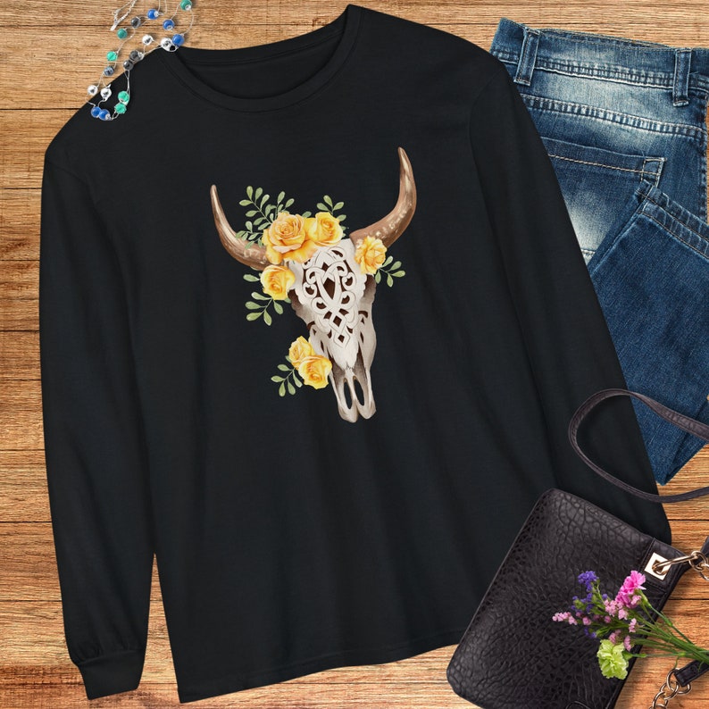 May include: Black long-sleeve t-shirt with a white bull skull design. The skull is adorned with yellow flowers.