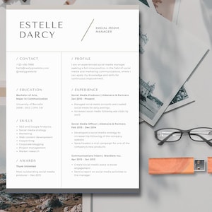 May include: A resume template with the name "Estelle Darcy" and the title "Social Media Manager" at the top. The resume includes sections for contact information, education, skills, and experience. A USB drive and eyeglasses are on the side.