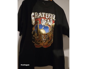 Puede incluir: Camiseta negra con un estampado gráfico colorido de un tigre y las palabras "Grateful Dead".