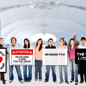 Puede incluir: Un grupo de amigos sosteniendo carteles con diferentes mensajes. Un cartel dice "Oh My Heck! Welcome Home" con un coraz&oacute;n rojo. Otro cartel dice "Atenci&oacute;n! I'm holding a sign for you, bruh!"  Un tercer cartel dice "We Missed You!" repetido varias veces. El &uacute;ltimo cartel dice "Two Years Later..."