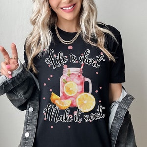 May include: Black t-shirt with a pink and white graphic of a mason jar filled with lemonade and the text "Life is short Make it sweet".