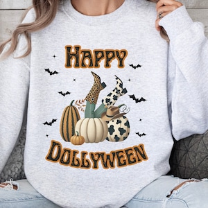 May include: A gray sweatshirt with the text "Happy Dollyween" printed on the front. The design features a pair of legs wearing cowboy boots and a leopard print skirt, with pumpkins and a cowboy hat.