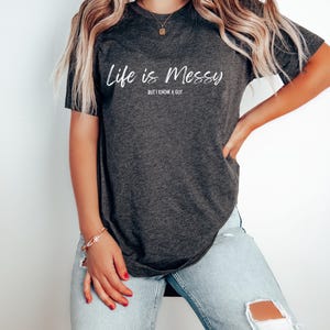 May include: A dark gray t-shirt with the text "Life is Messy but I know a Guy" in white lettering.