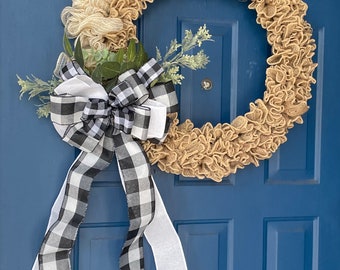 May include: A burlap and mesh wreath with a black and white checkered bow and greenery. The wreath is hanging on a blue door.