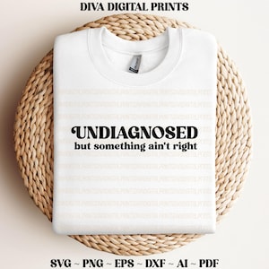 May include: White sweatshirt with the text "UNDIAGNOSED but something ain't right" in black retro-style lettering.