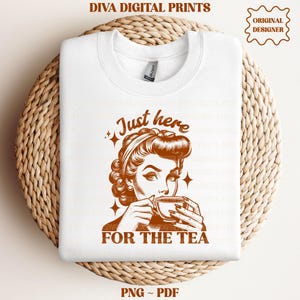 Może przedstawiać: Biała bluza z okrągłym dekoltem z brązowym nadrukiem graficznym przedstawiającym osobę w fryzurze vintage trzymającą filiżankę herbaty. Tekst brzmi Just here FOR THE TEA. Projekt zawiera małe czteroramienne gwiazdki jako akcenty.