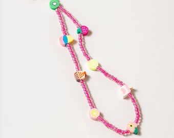 May include: A pink beaded phone strap with colorful fruit charms, including a kiwi, strawberry, pineapple, lemon, peach, and a star.