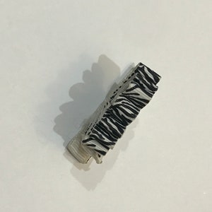 May include: A black and white zebra patterned hair clip.