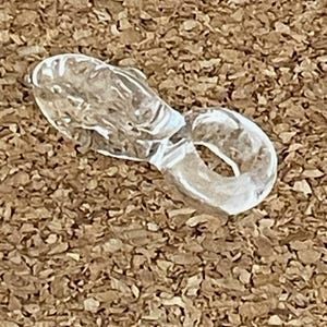 May include: A clear quartz crystal carved into the shape of a fish. The crystal is smooth and polished, with a translucent appearance. The fish is curled into a circle, with its tail touching its head.