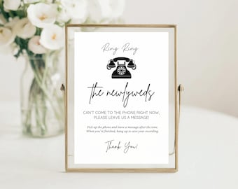 May include: A framed sign with the text "Ring Ring" and "the newlyweds" in elegant script. A black telephone graphic is centered above the text. The sign includes instructions for leaving a message and a "Thank You!" message.