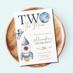 May include: A blue and white invitation card with a rocket ship, astronaut, and moon illustration. The text reads "Two the Moon" and "Alexander's 2nd Birthday". The date and time are listed as "Jan 26 | 1 PM".