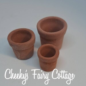 May include: Three terracotta flower pots of different sizes. The pots are unglazed and have a rustic appearance.