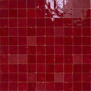 May include: A grid of small, square, glossy tiles in a deep red hue. The tiles are evenly spaced, creating a uniform pattern. The surface reflects light, highlighting the texture and color variations across the tiles.