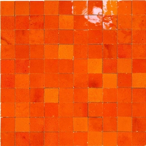 Op de afbeelding: Een mozaïek van vierkante oranje tegels in verschillende tinten, waardoor een gestructureerd, levendig oppervlak ontstaat. De tegels zijn in een rasterpatroon gerangschikt, waarbij sommige licht reflecteren, wat diepte aan het ontwerp toevoegt. Dit tegelmozaïek is geschikt voor interieurdecoratie.