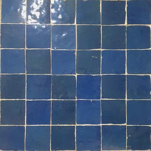 Peut inclure: Mosaïque de carreaux carrés bleus brillants, disposés en grille avec des joints blancs. Les carreaux présentent différentes nuances de bleu, créant un motif visuellement intéressant. L'ensemble forme une surface texturée et attrayante.
