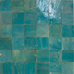 Puede incluir: Un conjunto de baldosas cuadradas en tonos turquesa y verde azulado. Las baldosas tienen una superficie brillante y ligeramente irregular, lo que sugiere una fabricación artesanal. La disposición crea un patrón repetitivo, ideal para un salpicadero o una pared decorativa.