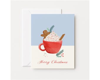 May include: A Christmas greeting card featuring a red mug of hot chocolate topped with whipped cream, a gingerbread man, and a cinnamon stick. The card has a light blue and white background with the words "Merry Christmas".