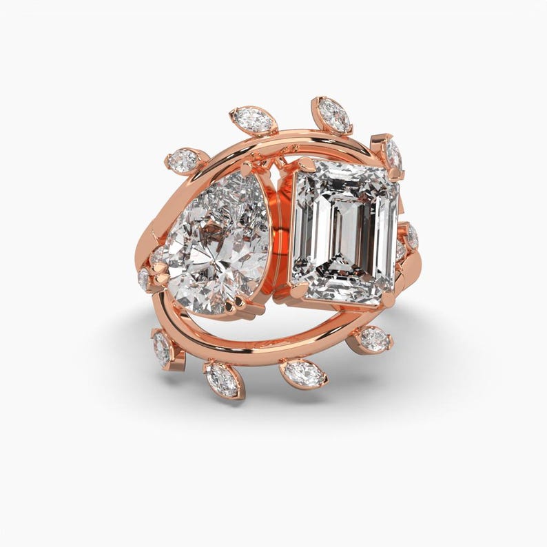 Puede incluir: Anillo de oro rosa con un diamante en forma de pera y talla esmeralda, acentuado con diamantes m&aacute;s peque&ntilde;os con talla marquesa. El anillo tiene un dise&ntilde;o floral, con los diamantes dispuestos en un delicado arreglo inspirado en la naturaleza.