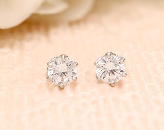 May include: A pair of silver stud earrings with clear round cubic zirconia stones.