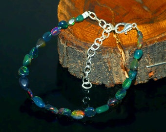 May include: A silver chain bracelet with a clasp closure. The bracelet is made with dark green and black opal beads.