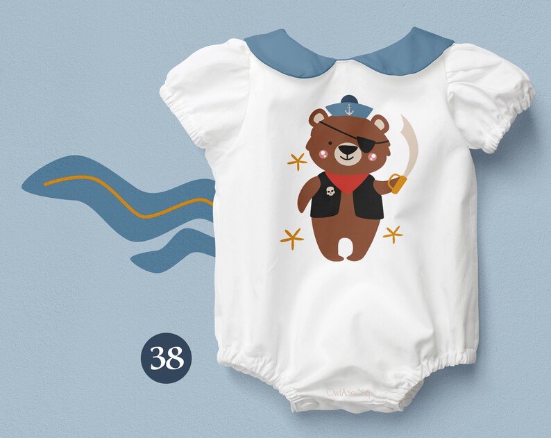May include: White baby onesie with a blue collar and a brown bear wearing a pirate hat and eyepatch. The bear is holding a sword and has a skull and crossbones on its vest. The onesie has a number 38 on the bottom left corner.