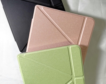 May include: Three tablet cases in black, rose gold, and light green. Each case has a geometric design with angular lines and a textured surface. The cases are stacked, showcasing their different colors and designs.